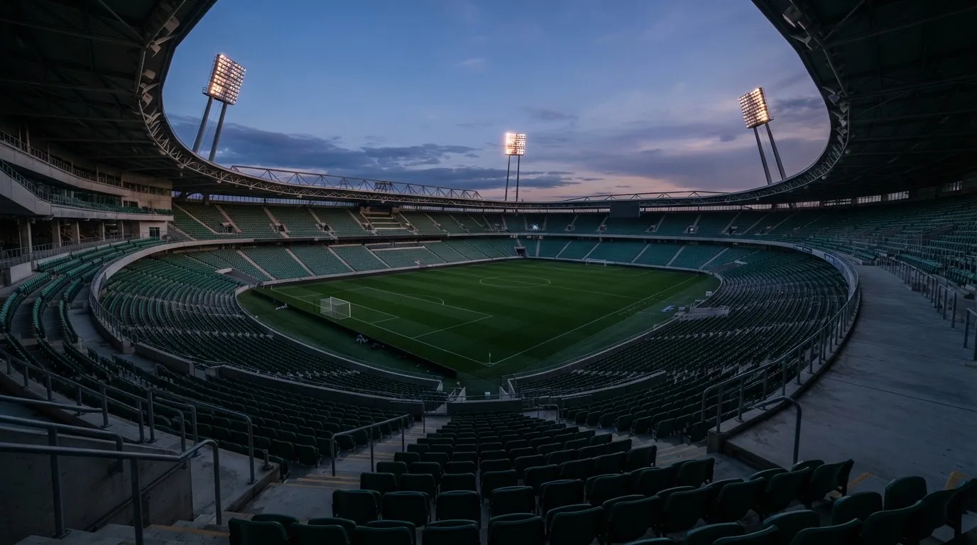 An empty football stadium with floodlight masts at dusk