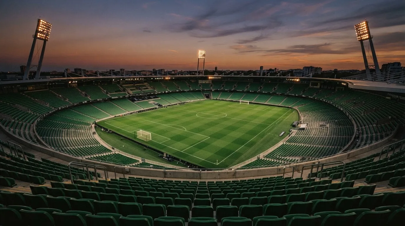 An empty football stadium with floodlight masts at dusk