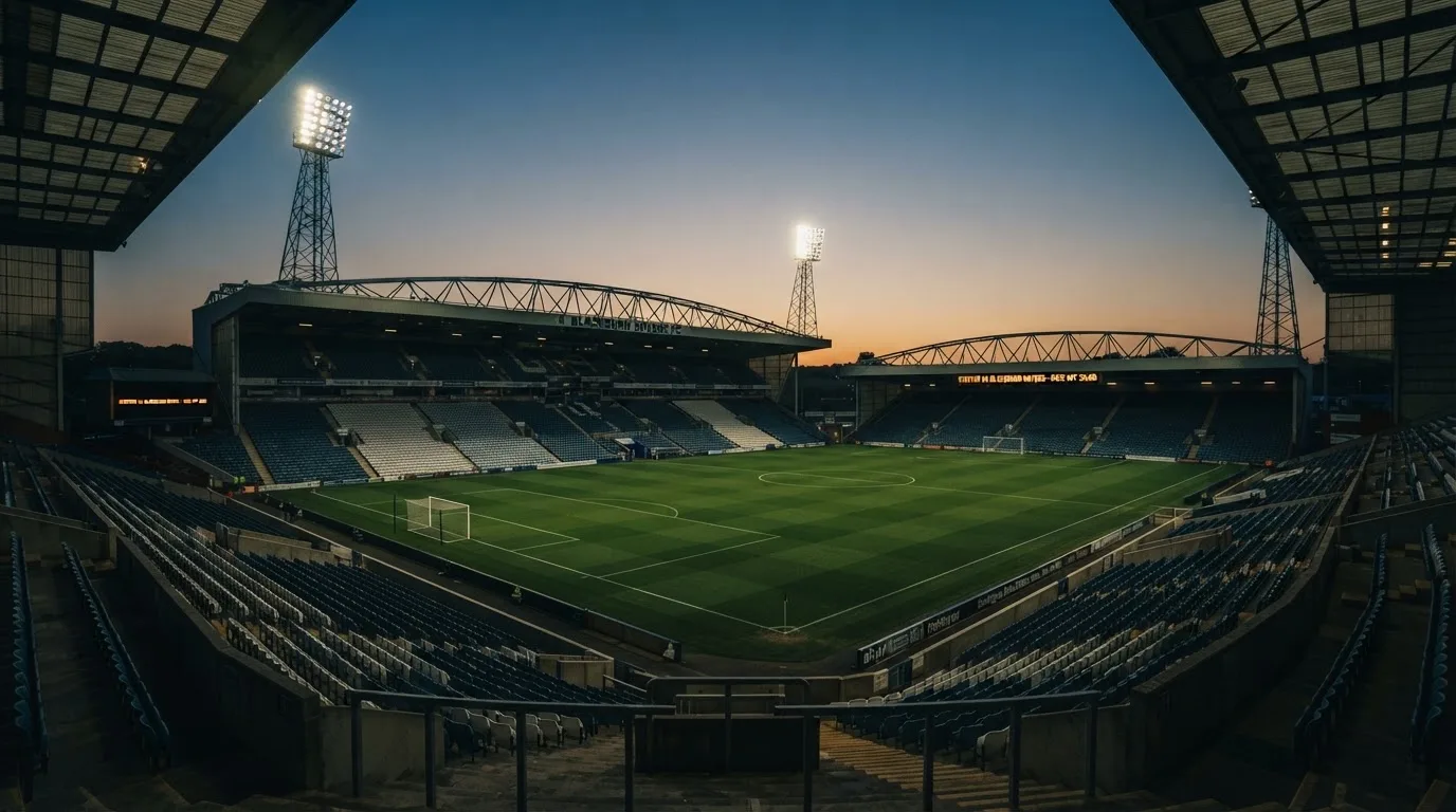 An empty football stadium with floodlight masts at dusk