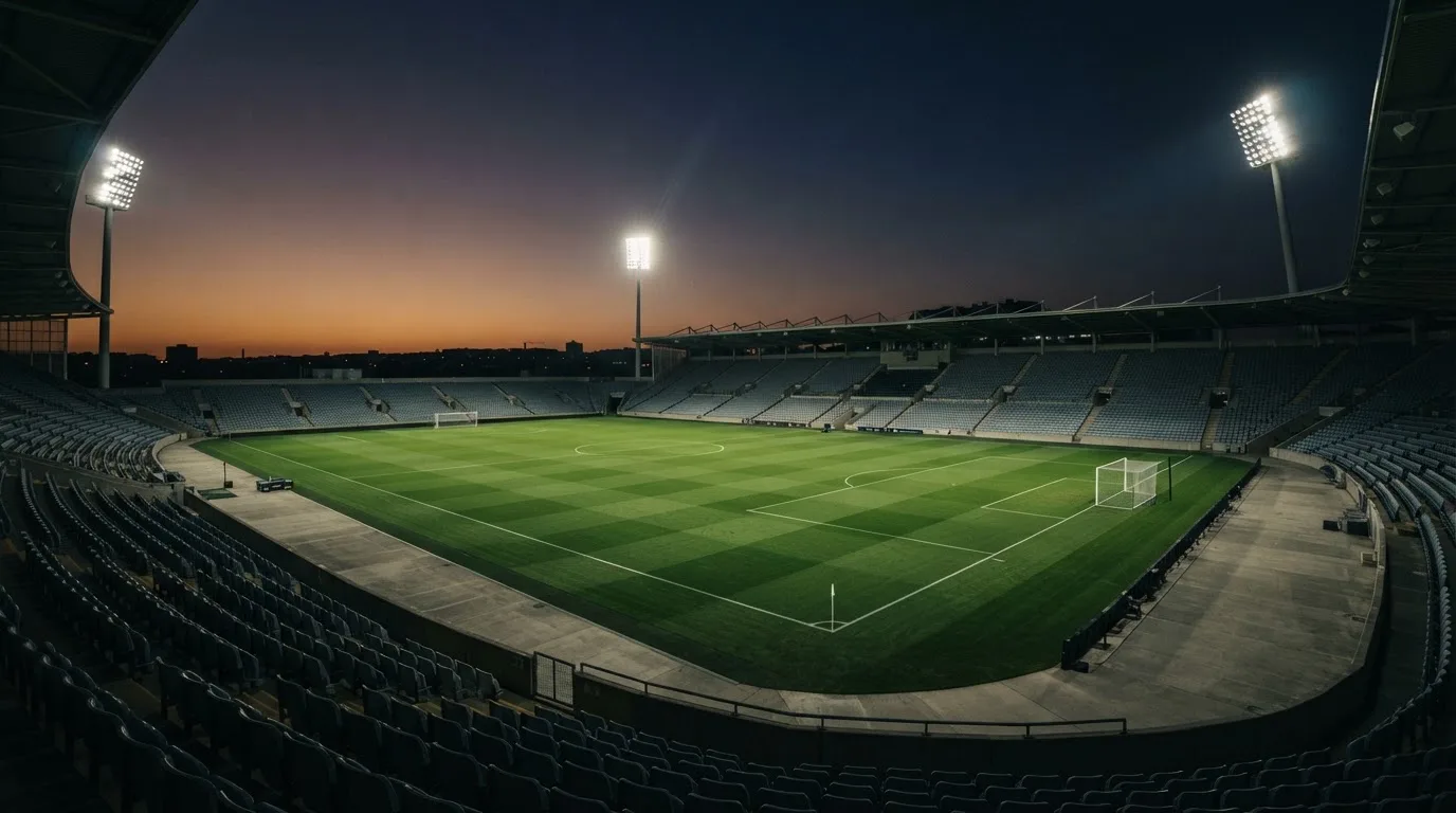 An empty football stadium with floodlight masts at dusk