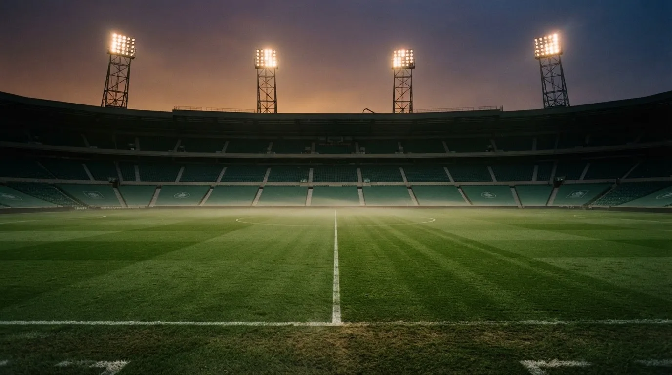 An empty football stadium with floodlight masts at dusk